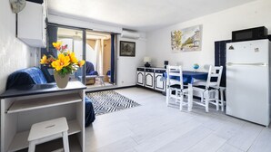 Un espacio habitable compacto con kitchenette, comedor y una pequeña zona de estar con vistas al exterior.
