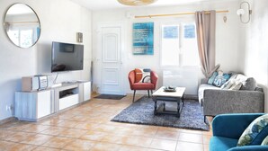 Ein Wohnzimmer mit Fernseher, Sofa, Sessel und Couchtisch.