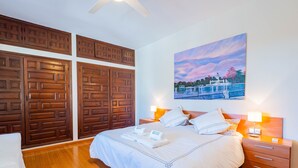 Una habitación de hotel con una cama grande, un armario de madera, una mesita de noche y un cuadro de un paisaje.