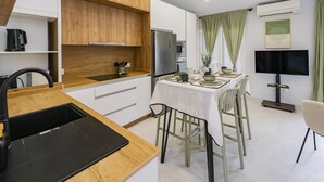 Una cocina moderna con armarios de madera, encimera negra y zona de comedor con mesa preparada para cuatro.