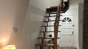 Una escalera de madera con barandilla que lleva a una puerta con un panel de vidrio.