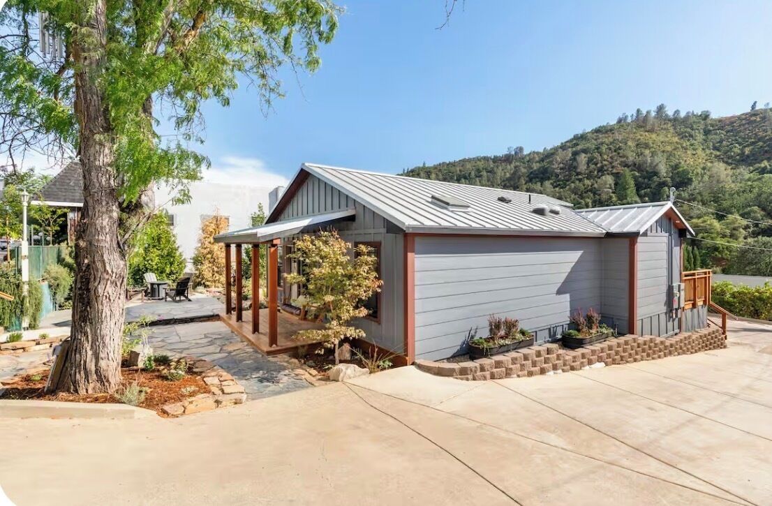 A single-story building with a garage, a covered porch, and a landscaped front yard.
