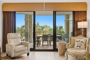 A room with a sliding glass door leading to a balcony with outdoor furniture and palm trees. - Florencia 107- Florcabana (Pensacola)