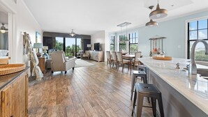 A spacious kitchen with a large island, wooden flooring, and modern pendant lighting.