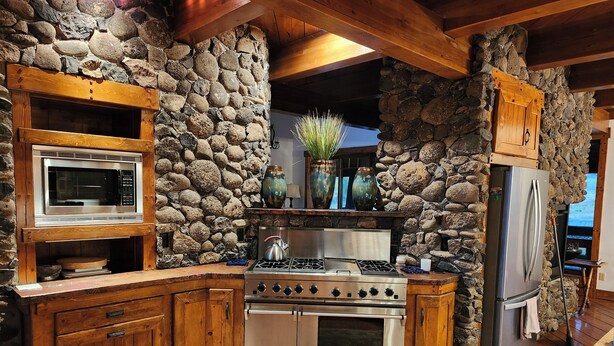 A rustic kitchen with stone walls, wooden cabinets, a built-in stove, a microwave, and a refrigerator. - Charming unique 2-bdrm farmhouse in Mesa with WiFi, close to Powderhorn Ski Area (Mesa)