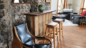 A rustic interior with a stone wall, wooden flooring, a leather chair, a wooden table, and a bar area. - Charming unique 2-bdrm farmhouse in Mesa with WiFi, close to Powderhorn Ski Area (Mesa)