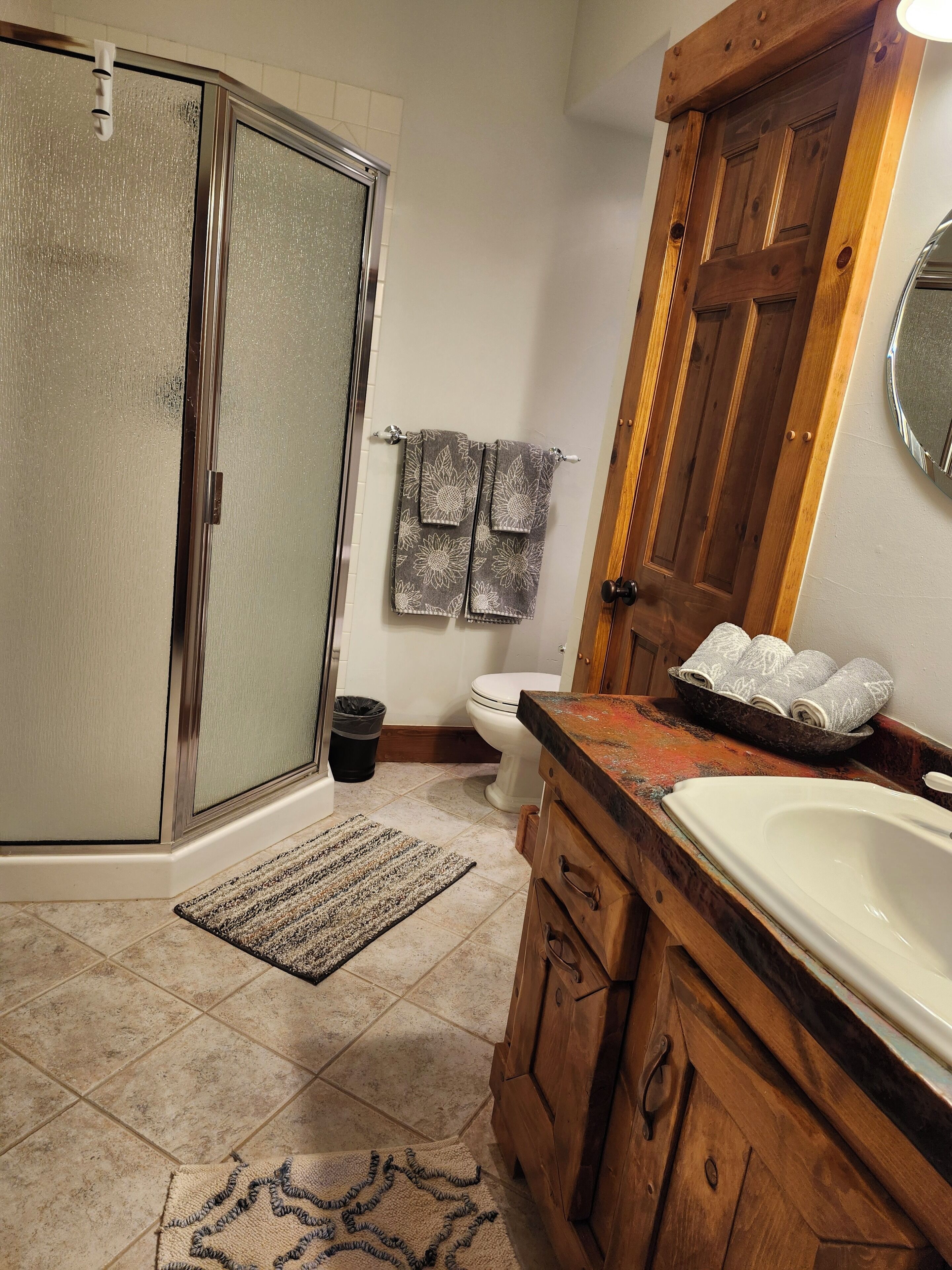 Un baño con ducha, inodoro, lavabo y tocador de madera.
