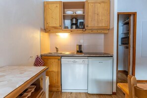 A compact kitchen with wooden cabinets, a dishwasher, and a microwave.