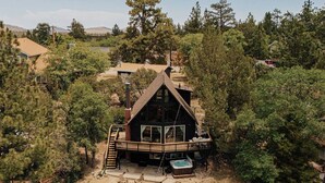 Une cabane avec une terrasse, un jacuzzi et un foyer extérieur.