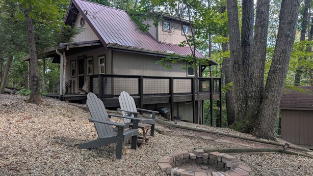 A cabin with a deck, two Adirondack chairs, and a fire pit. - Quaint Cabin w/ Elevated Back Deck Among the Trees (Laurelville)