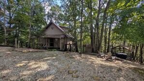 A cabin surrounded by trees with a gravel driveway and wooden deck. - Quaint Cabin w/ Elevated Back Deck Among the Trees (Laurelville)