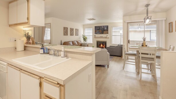 A modern kitchen with a central island, a dining area with a table and chairs, and a living room with a sofa and fireplace. - InThe Heart Of Downtown Boise! (Boise)