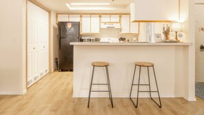 A modern kitchen with white cabinets, a stainless steel refrigerator, a built-in oven, and two wooden stools. - InThe Heart Of Downtown Boise! (Boise)