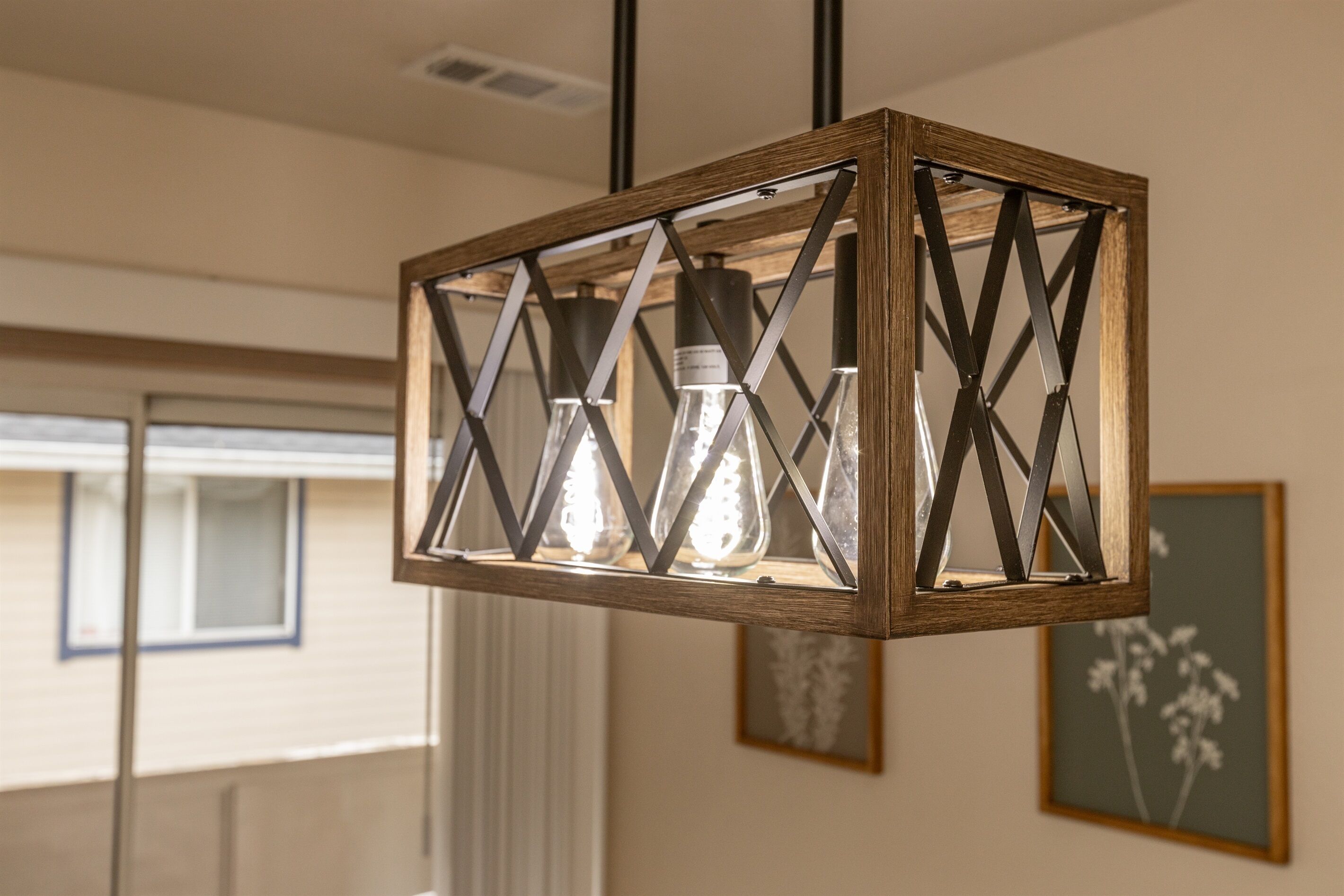 Un luminaire suspendu au design géométrique, dont les ampoules sont apparentes.