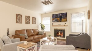 A living room with a brown leather sofa, a grey armchair, a white coffee table, and a fireplace. - InThe Heart Of Downtown Boise! (Boise)