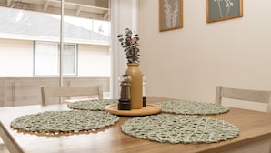A dining table with woven placemats, a vase with dried plants, and salt and pepper shakers. - InThe Heart Of Downtown Boise! (Boise)
