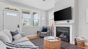 Una sala de estar con sofá, televisión, chimenea y ventilador de techo.