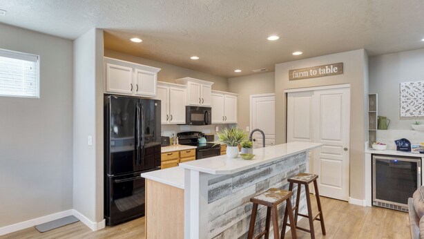 A modern kitchen with white cabinets, a black refrigerator, a microwave, and a farmhouse sink. - Old Mill Getaway by Avantstay Private Backyard w/ Hot Tub (Bend)
