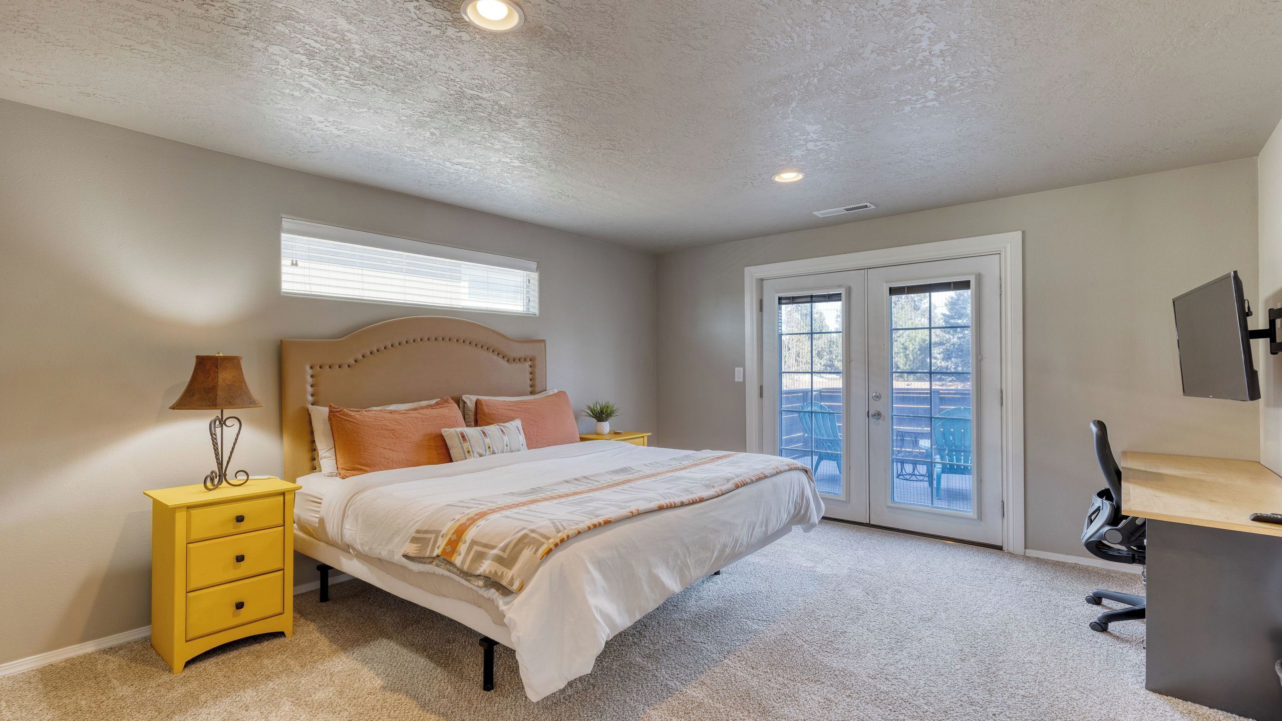 A bedroom with a bed, a nightstand, a desk, and a chair.