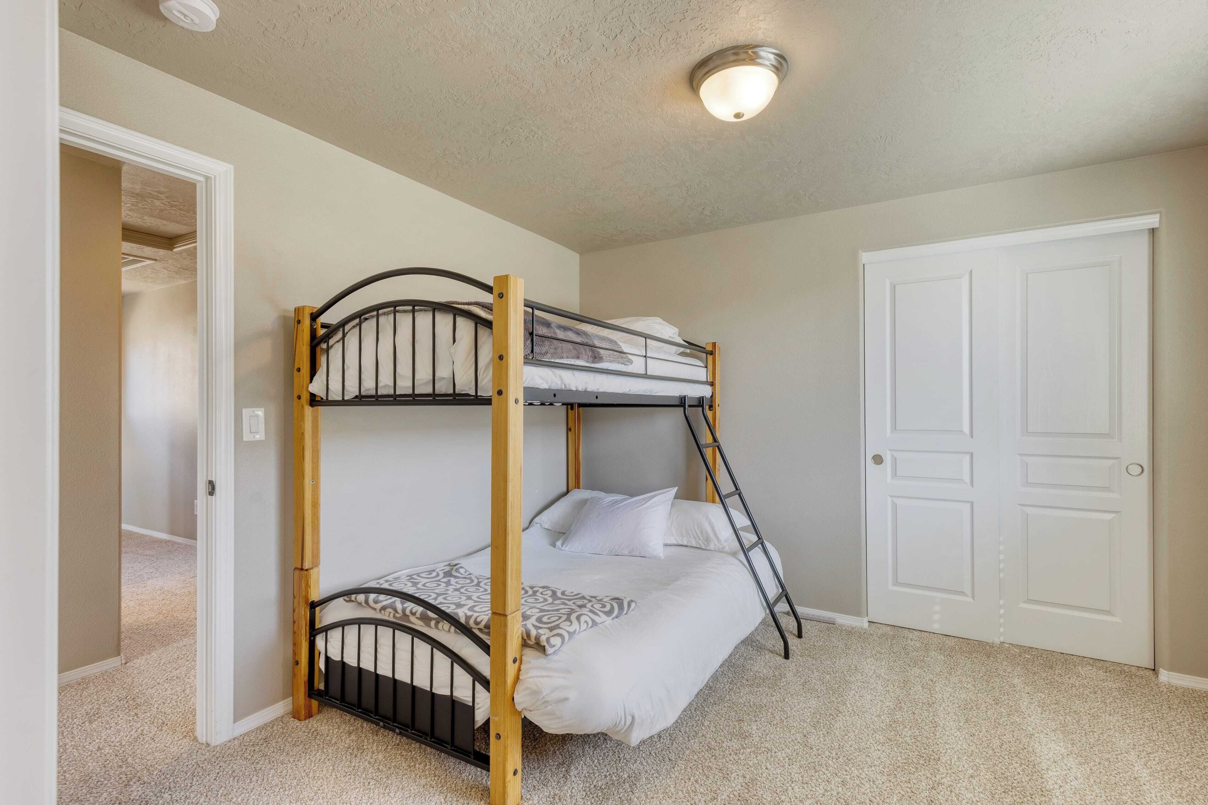 A bunk bed in a room with a door and a light fixture on the ceiling.