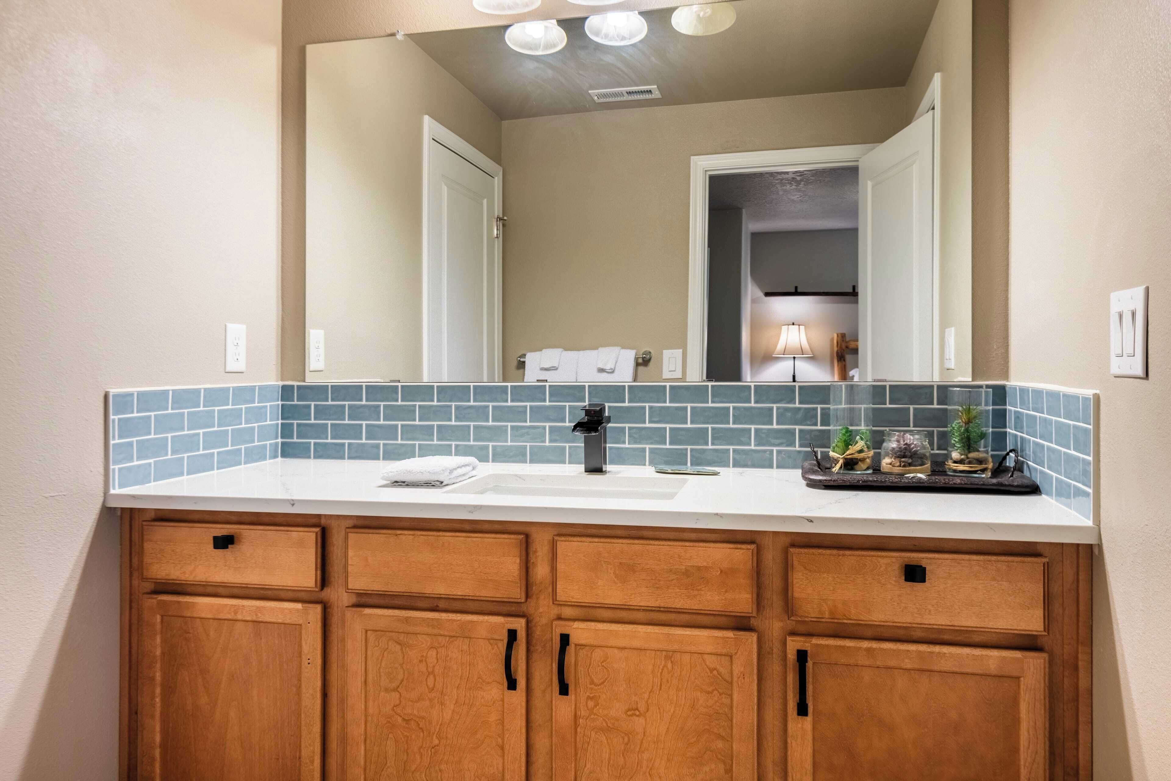 A bathroom with a wooden vanity, a sink, and a mirror.