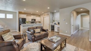 A spacious living room with a leather sofa, a coffee table, and a kitchen in the background. - Old Mill Getaway by Avantstay Private Backyard w/ Hot Tub (Bend)