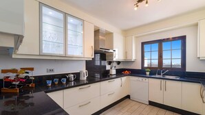 Une cuisine moderne avec des meubles blancs, un plan de travail noir et une fenêtre offrant une belle vue.