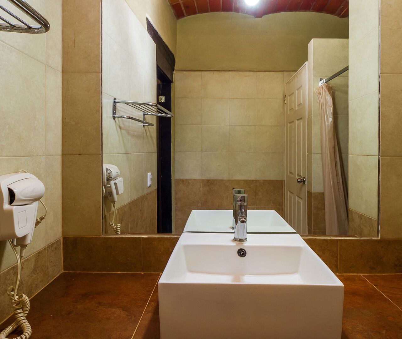 Un baño con lavamanos blanco, secador de pelo y barra para toallas.