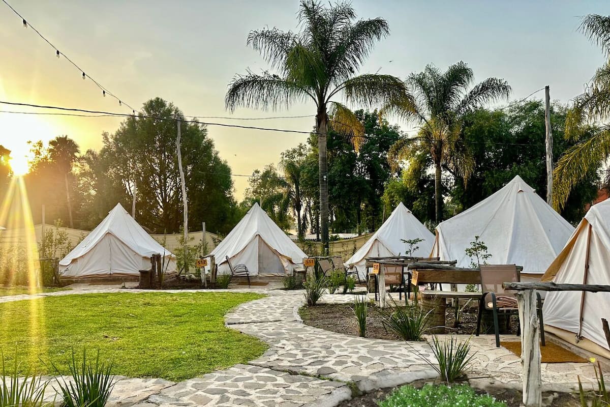 A campsite with several white tents, stone pathways, and outdoor seating areas.