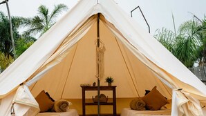 Een gezellige tent met twee bedden, een klein tafeltje en een hangende decoratie.