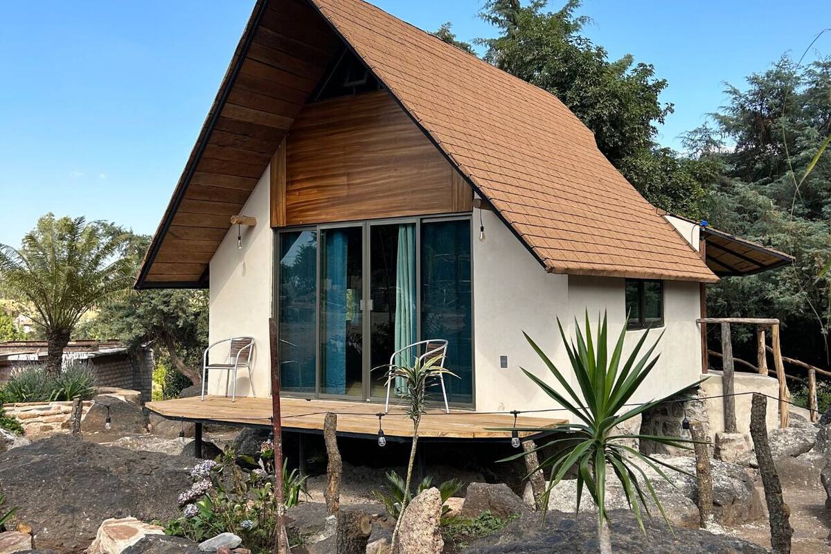 A modern house with a wooden roof, large sliding glass doors, and a wooden deck.