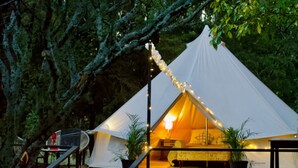 Een tent met een houten terras ervoor, omringd door bomen.