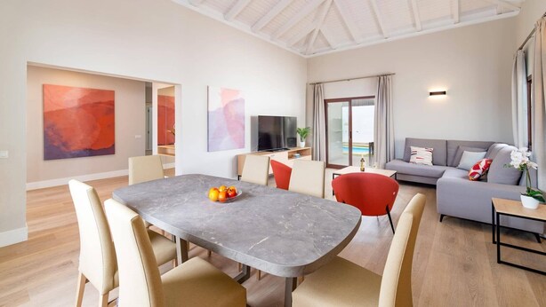 Una sala de estar moderna con comedor, televisor de pantalla plana y un ventanal con vistas.