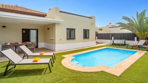 Una casa moderna con piscina, comedor y terraza cubierta.