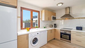 Una cocina moderna con lavadora integrada, microondas, horno y cafetera.