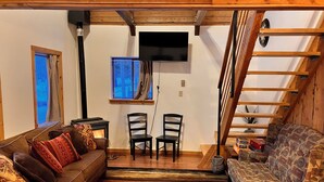 A cozy living room with a fireplace, two chairs, a sofa, and a TV mounted on the wall. - Cozy Woodland Escape: Scenic Cabin Retreat in Alpine, WY (Alpine)