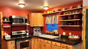 A kitchen with wooden cabinets, a stainless steel stove, a microwave, and a window with a view. - Cozy Woodland Escape: Scenic Cabin Retreat in Alpine, WY (Alpine)