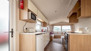 A compact kitchen with wooden cabinets, a microwave, a dishwasher, and a stove.