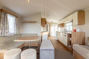 A modern RV interior with a dining area, kitchenette, and seating space.