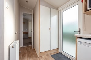 A narrow hallway with a door leading to a bedroom, a radiator, and a view through a frosted glass door.