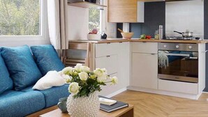 Une cuisine moderne avec des meubles en bois, un four à micro-ondes et un four traditionnel. On y trouve un canapé bleu avec un coussin blanc et un vase de fleurs posé sur une table en bois.