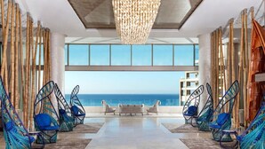 Un salon moderne avec des fauteuils suspendus, un banc et une vue sur l’océan.