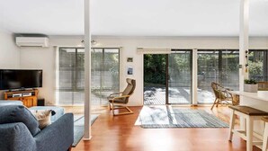 Ein modernes Wohnzimmer mit einer Couch, einem Fernseher und einem Essbereich mit Stühlen.