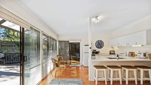Eine moderne Küche mit großem Fenster, einem Essbereich mit Stühlen und einer Bar mit Sitzhockern.