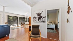 Ein modernes Wohnzimmer mit großem Fenster, einer Couch, einem Sessel und einem Gemälde eines Stiers an der Wand.