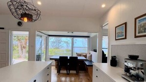 A modern kitchen with a central island, wooden flooring, and a coffee machine. - The Gem at Depot Beach (Depot Beach)