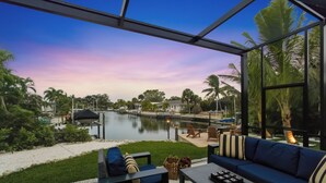 A modern outdoor seating area with a view of a water body and palm trees.