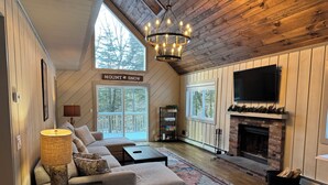 Un salon confortable avec une cheminée, un grand téléviseur et une enseigne sur laquelle on peut lire « MOUNT SNOW ».