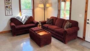 A living room with two red sofas, a wooden coffee table, and a floor lamp.