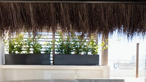 A restaurant with a thatched roof, blue chairs, and a stone counter. - SUUT Hostal Boutique (Playa del Carmen)